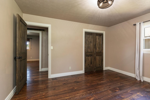 unfurnished bedroom featuring dark wood-style floors, baseboards, and a closet