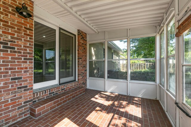 unfurnished sunroom featuring healthy amount of natural light and beam ceiling