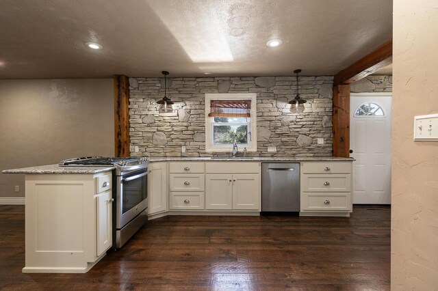 kitchen with stainless steel appliances, a sink, a peninsula, white cabinets, and dark wood finished floors