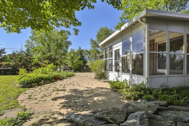 view of side of home with a sunroom and a patio