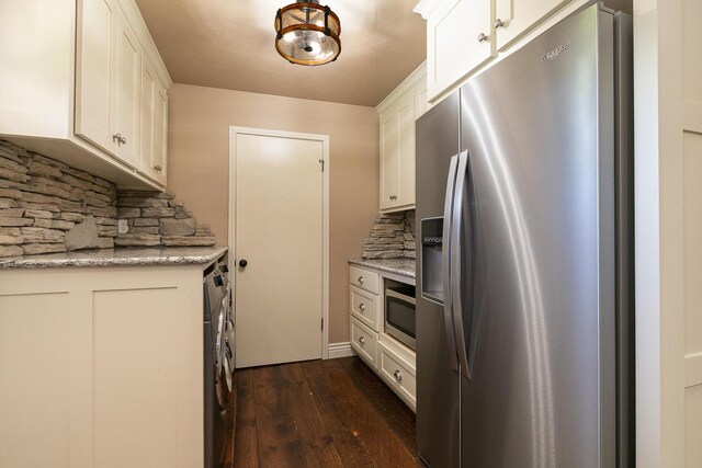kitchen with appliances with stainless steel finishes, dark wood-style floors, decorative backsplash, white cabinets, and washing machine and dryer