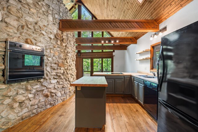 kitchen featuring black appliances, open shelves, light wood finished floors, gray cabinetry, and a sink