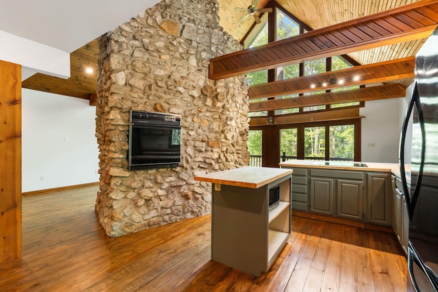 kitchen with black appliances, tile countertops, high vaulted ceiling, wood-type flooring, and open shelves