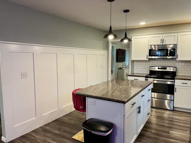 kitchen featuring appliances with stainless steel finishes, tasteful backsplash, a kitchen island, dark wood-style flooring, and white cabinets