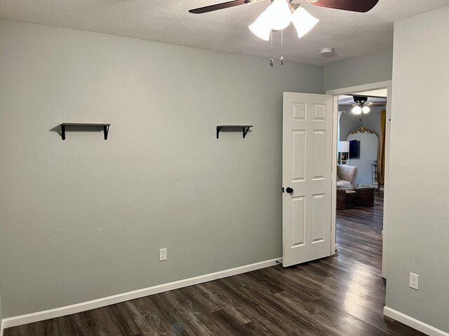 empty room featuring ceiling fan, dark wood-style floors, and baseboards