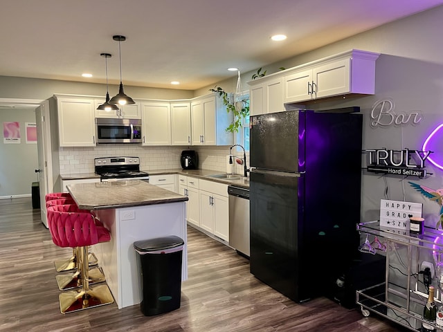 kitchen featuring appliances with stainless steel finishes, a sink, white cabinetry, dark wood-style flooring, and recessed lighting