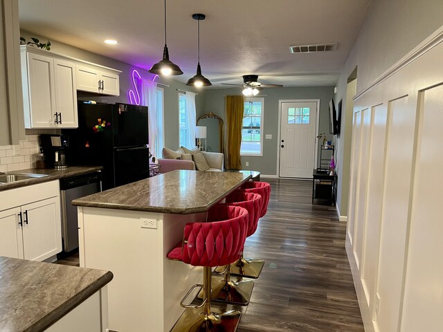 kitchen featuring dishwasher, dark countertops, white cabinetry, a kitchen island, and freestanding refrigerator