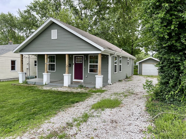 view of front of property with gravel driveway, a porch, an outbuilding, a garage, and a front lawn