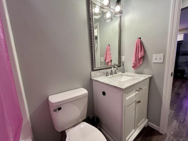 half bathroom featuring toilet, vanity, and wood finished floors