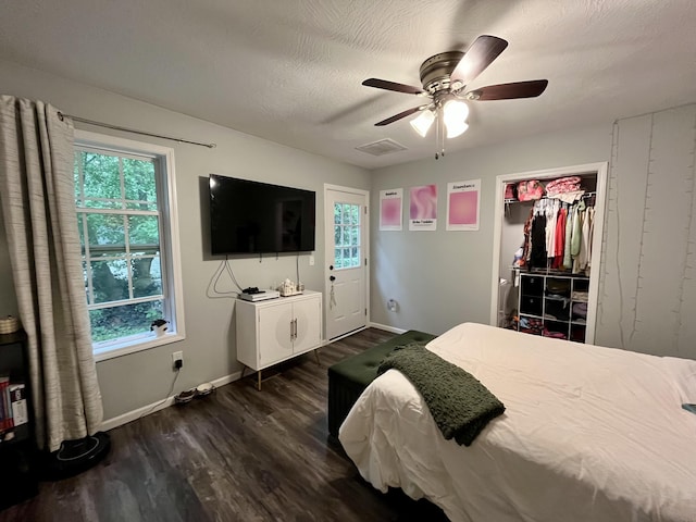 bedroom with dark wood-type flooring, multiple windows, baseboards, a ceiling fan, and a textured ceiling