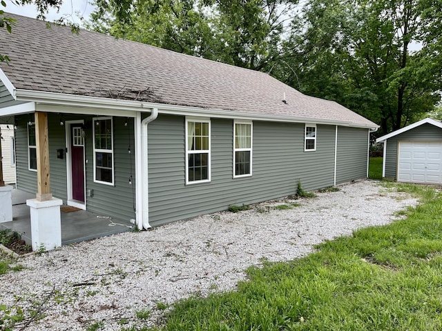 view of side of home featuring an outdoor structure, roof with shingles, and a detached garage