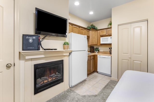 kitchen with white appliances, light tile patterned floors, light countertops, recessed lighting, and a fireplace