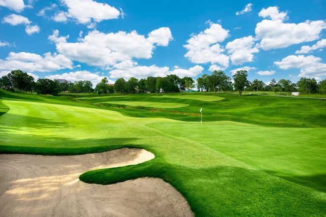 surrounding community featuring view of golf course and view of scattered trees