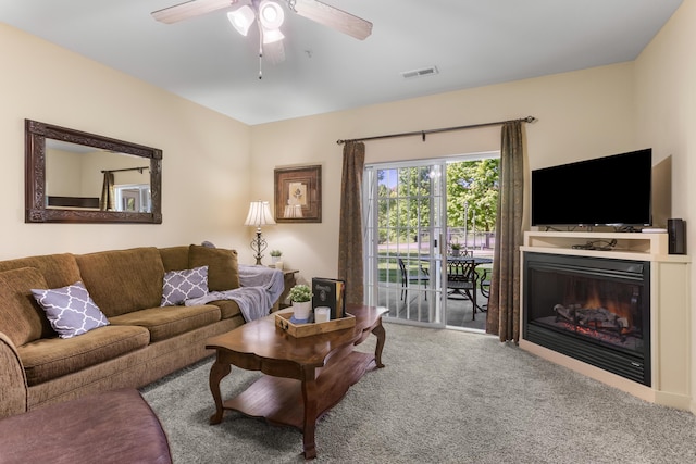 carpeted living room with a ceiling fan and a glass covered fireplace