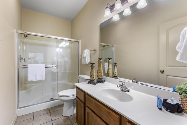 bathroom with toilet, tile patterned floors, a stall shower, and vanity