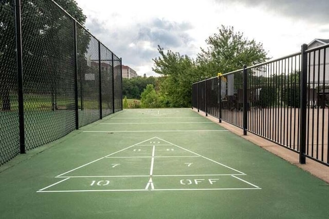 view of community featuring fence and shuffleboard