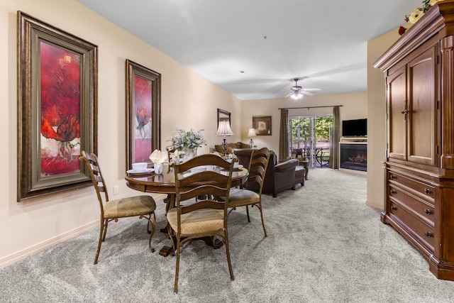 dining room with light colored carpet, a ceiling fan, and baseboards