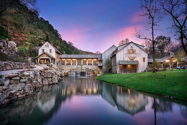 back of property with a yard, a water view, and stone siding