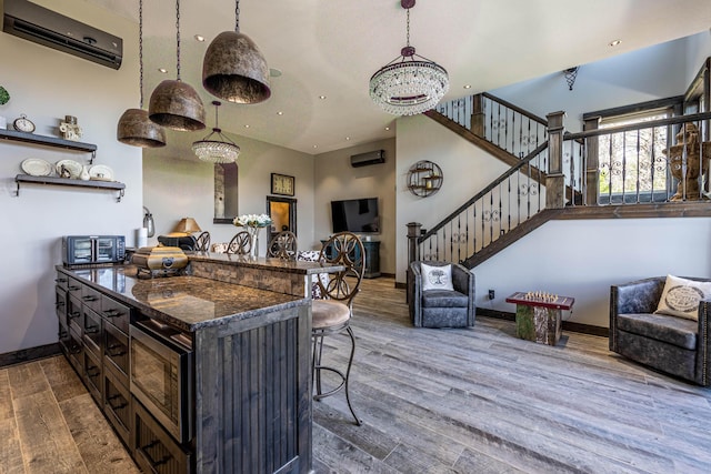 3701 S 1500th Rd, Rich Hill, MO 64779 - kitchen with a wall mounted AC, open floor plan, a kitchen breakfast bar, dark wood finished floors, and dark stone countertops