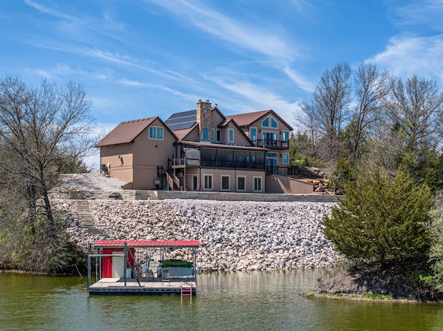 3701 S 1500th Rd, Rich Hill, MO 64779 - back of house with a water view, a balcony, stucco siding, and a chimney
