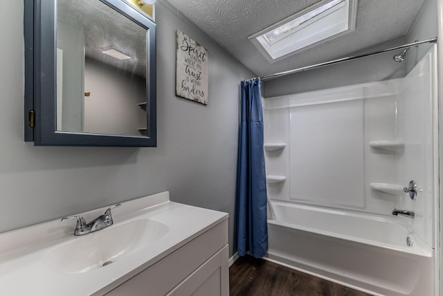 full bathroom featuring wood finished floors, a textured ceiling, shower / bathtub combination with curtain, a skylight, and vanity