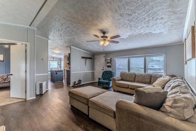 living room featuring ceiling fan, plenty of natural light, dark wood-type flooring, ornamental molding, and a textured ceiling