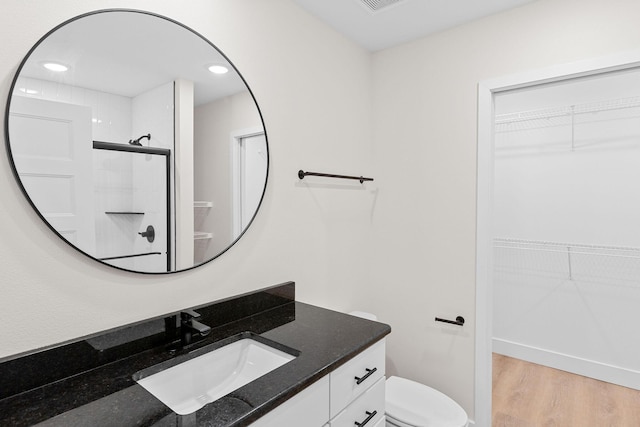 335 Mccann Rd, Powersite, MO 65731 - bathroom featuring toilet, vanity, a spacious closet, a shower, and wood finished floors