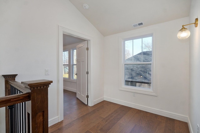 corridor with dark wood-style floors, lofted ceiling, baseboards, and an upstairs landing