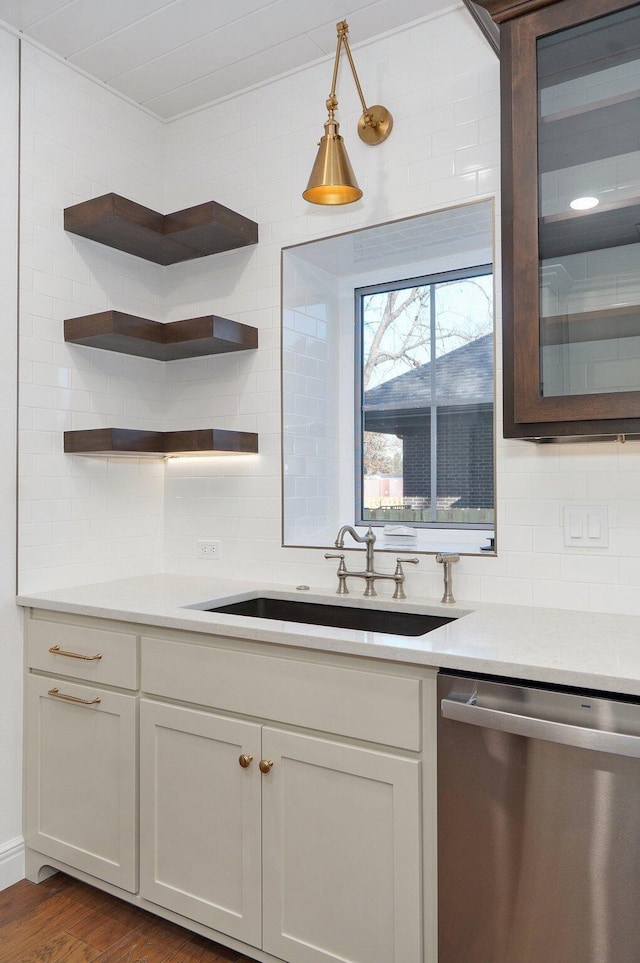 kitchen with dishwasher, a sink, backsplash, dark wood-type flooring, and light countertops