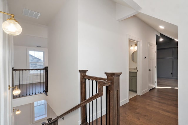 hallway with an upstairs landing, dark wood-style floors, and baseboards