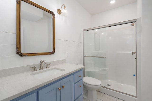 full bath with a stall shower, toilet, vanity, and tile walls