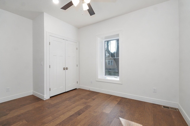 unfurnished bedroom with dark wood-type flooring, baseboards, a ceiling fan, and a closet