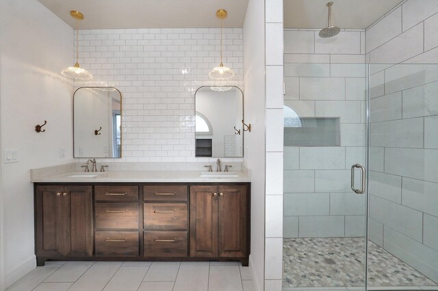 full bathroom featuring a stall shower, double vanity, tile patterned floors, and baseboards