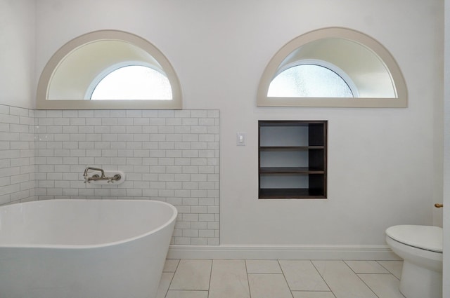 bathroom featuring built in features, healthy amount of natural light, a soaking tub, and toilet