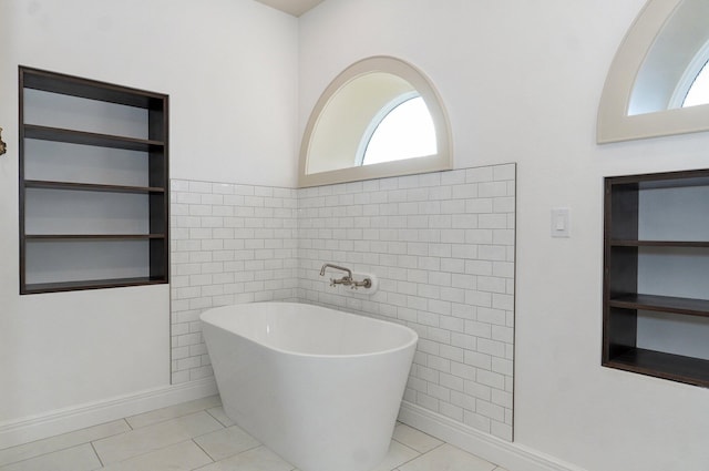 bathroom featuring a freestanding bath, plenty of natural light, tile walls, and tile patterned floors