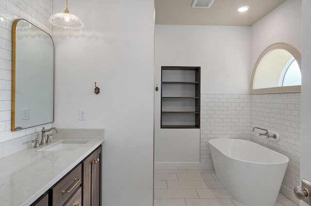 full bathroom featuring vanity, a freestanding tub, tile patterned floors, and tile walls