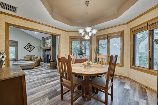 5425 S Westwood Ave, Springfield, MO 65810 - dining room featuring a raised ceiling, wood finished floors, a chandelier, a large fireplace, and plenty of natural light