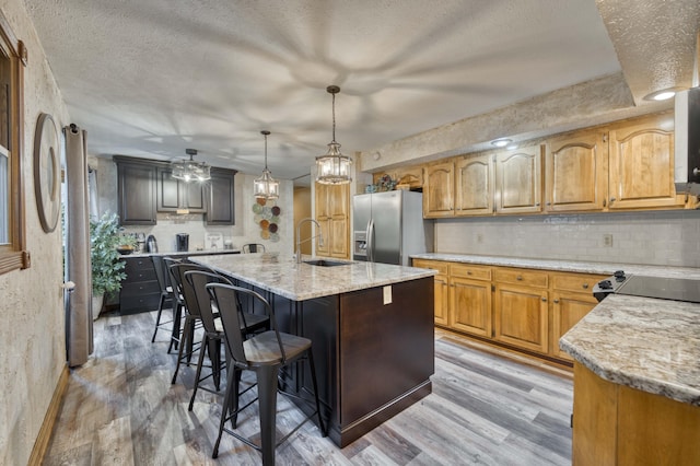 5425 S Westwood Ave, Springfield, MO 65810 - kitchen with stainless steel fridge with ice dispenser, a sink, light wood-style flooring, light stone counters, and decorative backsplash