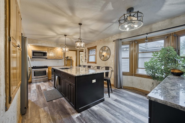5425 S Westwood Ave, Springfield, MO 65810 - kitchen featuring appliances with stainless steel finishes, a sink, dark wood-style floors, a kitchen breakfast bar, and an island with sink