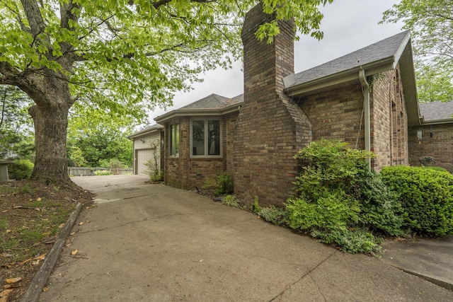 5425 S Westwood Ave, Springfield, MO 65810 - view of property exterior with a chimney, concrete driveway, brick siding, and an attached garage