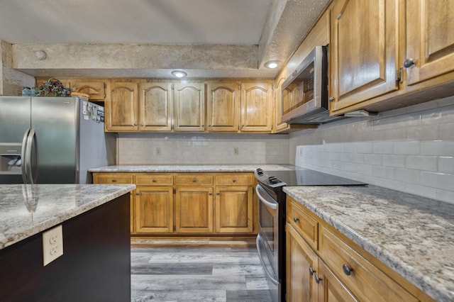 5425 S Westwood Ave, Springfield, MO 65810 - kitchen featuring stainless steel appliances, light wood-style floors, brown cabinetry, backsplash, and light stone counters