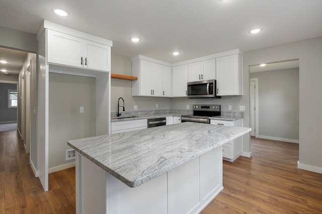 610 Chicago Ave, Marionville, MO 65705 - kitchen with stainless steel appliances, a sink, baseboards, wood finished floors, and white cabinets