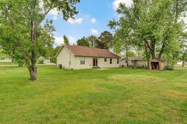 rear view of property featuring a yard, central AC, a shed, an outdoor structure, and entry steps