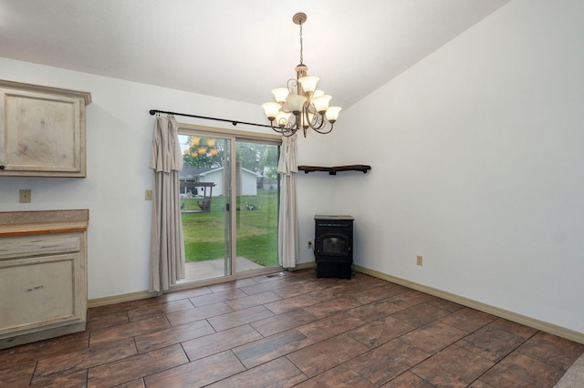 unfurnished dining area featuring a chandelier, a wood stove, baseboards, and vaulted ceiling