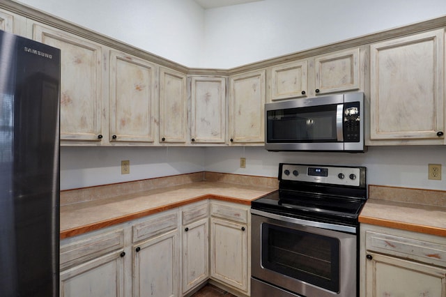 kitchen featuring appliances with stainless steel finishes, light countertops, and cream cabinets