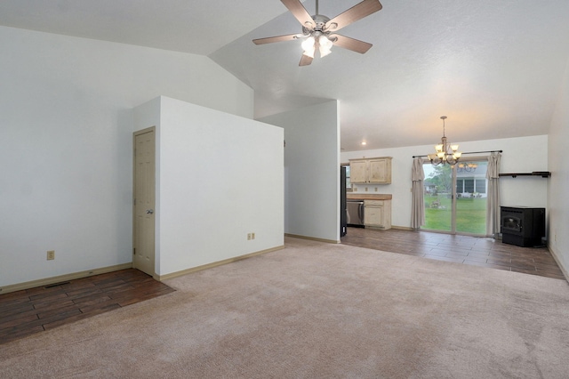 unfurnished living room featuring vaulted ceiling, light carpet, a wood stove, a chandelier, and ceiling fan