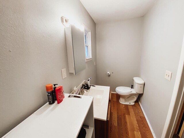 310 W Delta St, Aurora, MO 65605 - half bathroom with wood finished floors, toilet, vanity, and baseboards