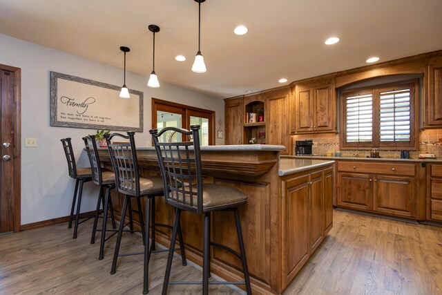 1918 E Buena Vista St, Springfield, MO 65804 - kitchen with brown cabinetry, recessed lighting, open shelves, a kitchen bar, and light wood-style floors