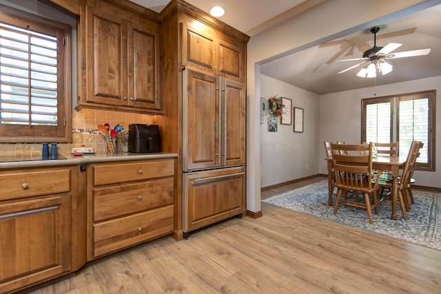 1918 E Buena Vista St, Springfield, MO 65804 - kitchen with brown cabinets, paneled built in refrigerator, a ceiling fan, light wood-style flooring, and decorative backsplash