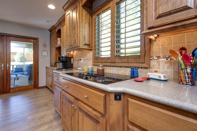 1918 E Buena Vista St, Springfield, MO 65804 - kitchen with black electric stovetop, backsplash, brown cabinetry, light wood-style floors, and recessed lighting
